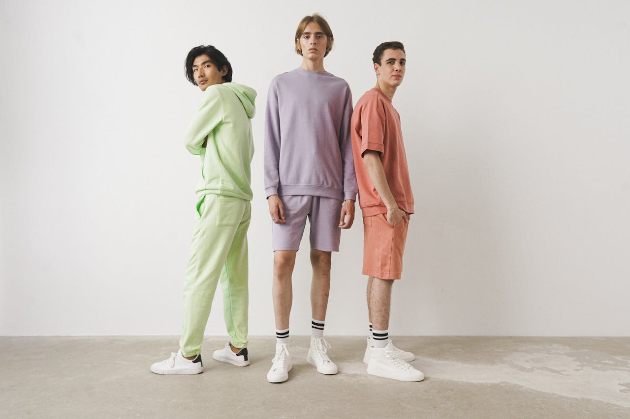 Home Three men in pastel casual outfits posing in a studio setting.